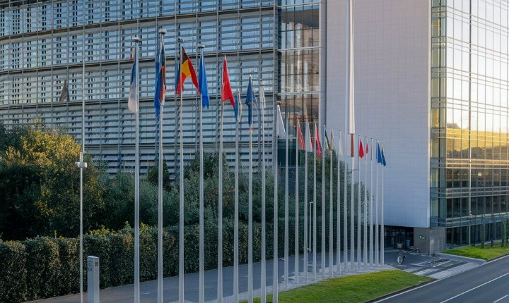 Image de la Commission Européenne : immeuble haut avec drapeaux des pays membres et drapeau européen