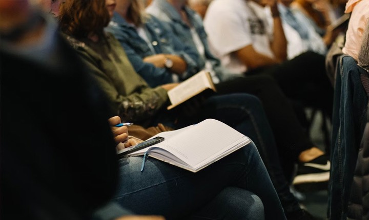 Photo prise dans une salle de conf&eacute;rence montrant une personne prenant des notes